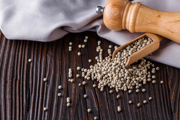 white peppercorns in wooden scoop on rustic background