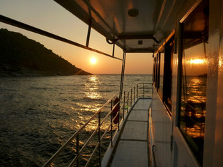The setting sun reflected off the waves and the windows of a boat off the coast of Thailand