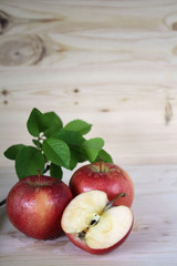 Red apples with a sprig of leaves on a wooden table