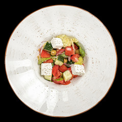 Greek salad with olives and cheese on a round white plate top photo, isolate, black background