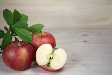 Red apples with a sprig of leaves on a wooden table