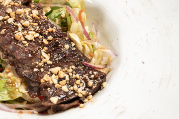 warm salad with beef on a round white plate