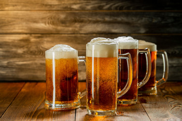 light beer with foam in mugs on a wooden table
