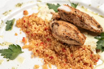 chicken breast with a side dish of cereals on a white plate