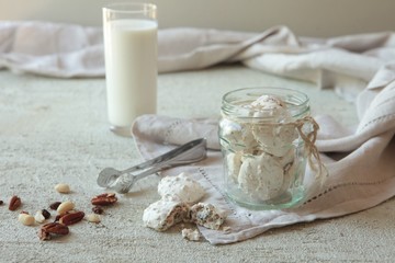 Traditional Beze or Meringues with nuts in a glass jar on concrete background. Copy space. A glass of milk. Homemade Meringue made with love.