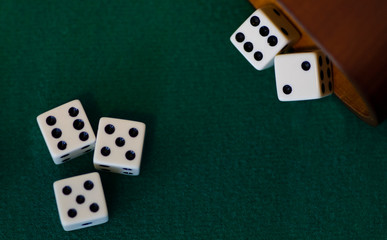 Five dice or die rolled out or a Yahtzee cup onto a green game table.