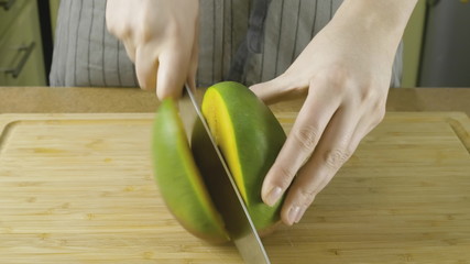Woman hands unfolds cutted by pieces fresh yellow mango in close up video in 4K