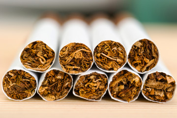 Close-up of a pile of cigarettes with perspective on a wooden table.