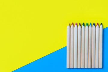 Colored pencils on a blue-yellow background. Copy space, flat layout, mockup. Back to school.