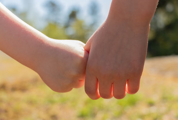 Two kids holding hands, closeup. Childhood, friendship and love concept.