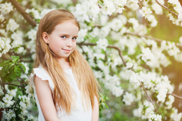 Naklejka premium Beautiful preteen girl with long blond hair enjoy spring apple blooming. Little preschool girl in garden tree flowers. Copy space for text.