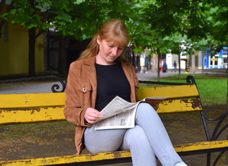 young woman reading a newspaper in the park