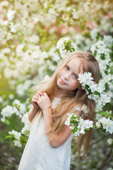 Obraz premium Beautiful preteen girl with long blond hair enjoy spring apple blooming. Little preschool girl in garden tree flowers. Vertical shot with copy space.