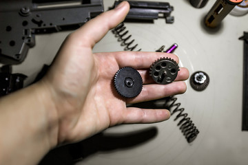 closeup metal gears lie on man&rsquo;s hand disassembled gearbox, repair airsoft guns