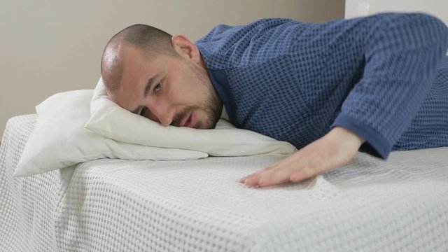 Portrait of a obese man with difficulty doing exercises on the bed. Lazy man and sport