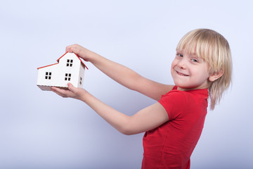 Smiling kid holding model home. Buying home, mortgage concept