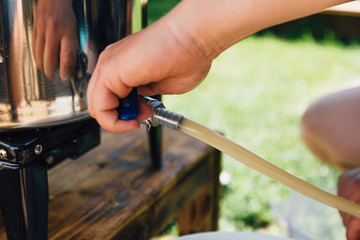 Mann betätigt Kugelhahn zum Ablassen der Maische