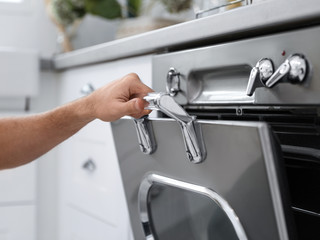 Man using modern oven in kitchen, closeup