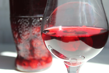 A glass of red compote. Cherry compote in a decanter next to a glass