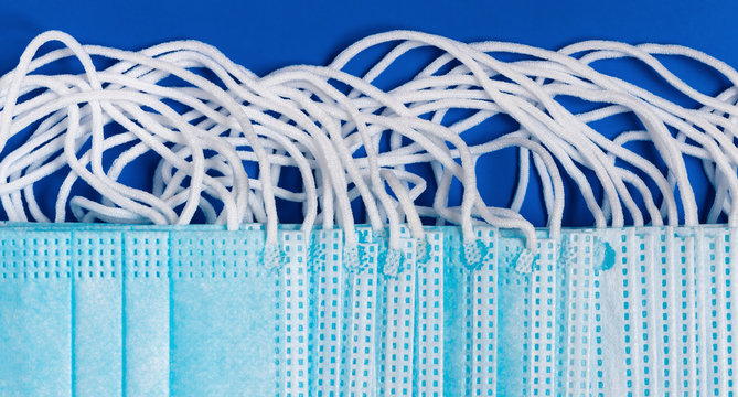 Close-up view of virus protection face mask with rubber ear straps on blue background as protection concept. Flat lay banner