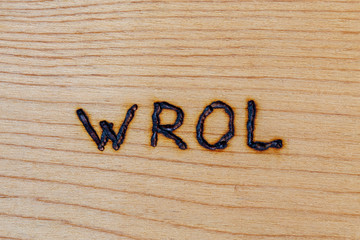 the abbreviation wrol - Without Rule Of Law - handwritten with woodburner on flat wooden surface