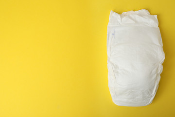 Baby diaper on yellow background, top view. Space for text