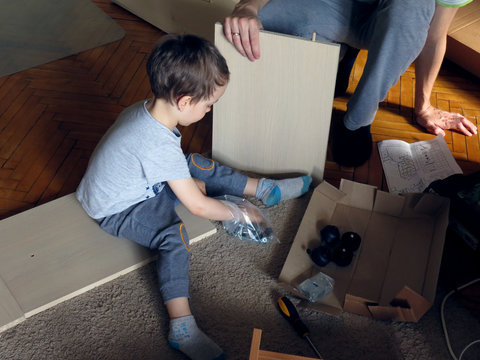 The Son Helps Dad To Collect Furniture, Nearby Are Tools And Boards. 