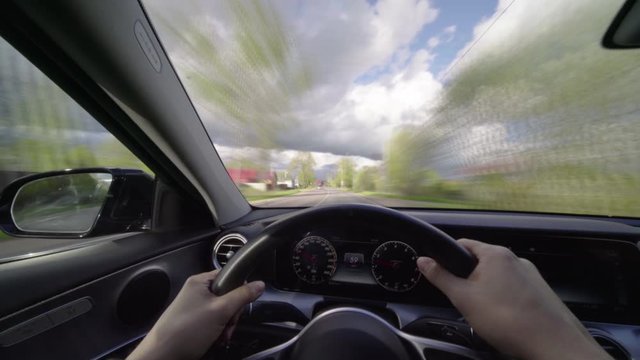 Driver holds both hands on steering wheel as he drives his car at clody day Timelapse