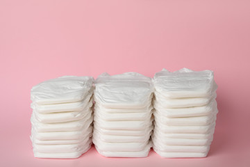 Stacks of baby diapers on pink background
