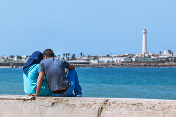 Fototapeta na wymiar Muslim couple sitting at sea front 