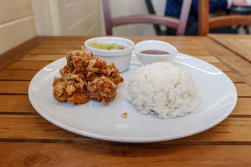 Selected focus view at homey meal style of Karaage or Japanese fried chicken serve with miso soup, salad and steamed rice on side, on wooden table in Japanese restaurant. 