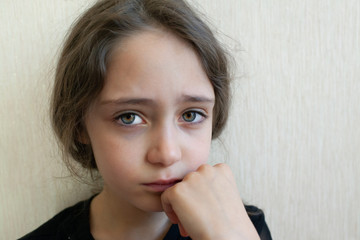 Portrait of a girl of 8 years old crying and sad on a light background