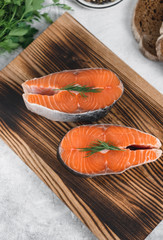 Fresh steaks of red salmon fish with spices and herbs on a wooden board. Healthy food.