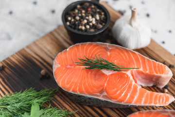 Fresh steaks of red salmon fish with spices and herbs on a wooden board. Healthy food.