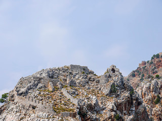 The ruins of an ancient fortress located among the mountains in Europe. Dilapidated chapel on the mountain and the fortress wall.