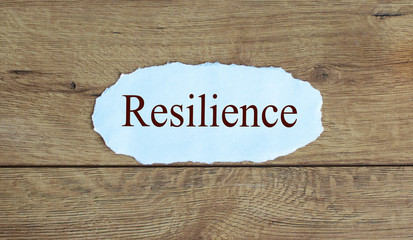 Text 'resilience' on the piece of paper. Beautiful wooden background. Business concept.