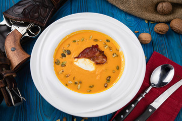 pumpkin soup with fried bacon on wooden background