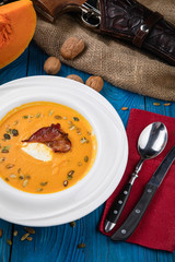 pumpkin soup with fried bacon on wooden background