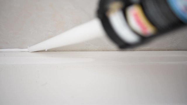 4K detail footage of a cannula applying silicone to the seal of a bathroom sink