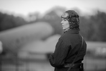 Retro style black and white photography. A young female pilot in uniform of Soviet Army pilots...