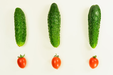 Ripe cucumbers and cherry tomatoes laid out on a white background in the form of trez exclamation marks