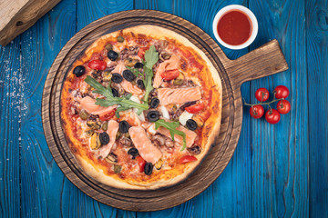Italian pizza with salmon and olives on blue background