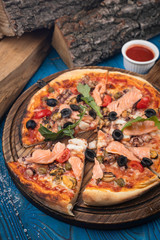 Italian pizza with salmon and olives on blue background