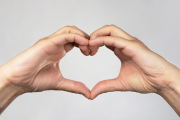 Two hands folded in the shape of a heart on a rough background