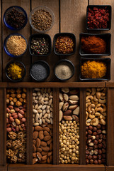 Mix of spices and mix of nuts on a wooden surface