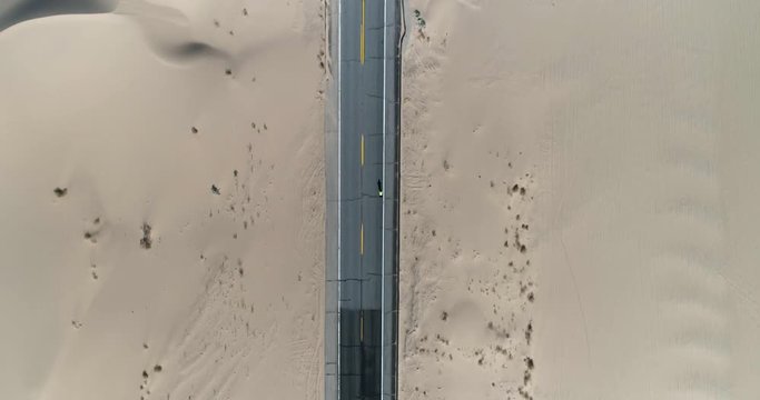 Birds eye view of cyclist riding through desert sand dunes 