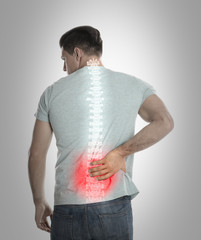 Man suffering from pain in spine on grey background