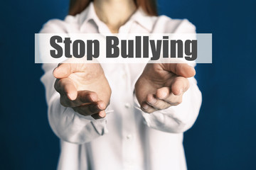 Young woman showing sign STOP BULLYING on blue background, closeup