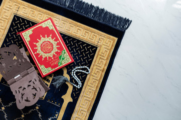 Muslim Holy Quran and rosary or tasbih with praying mat rug or sejadah isolated white