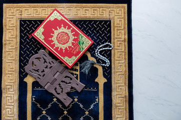 Muslim Holy Quran and rosary or tasbih with praying mat rug or sejadah isolated white